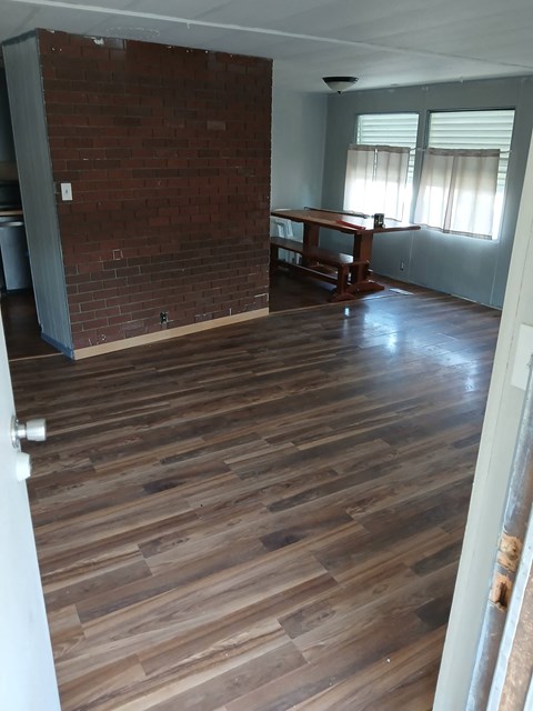 A room with a wooden floor and a brick wall.