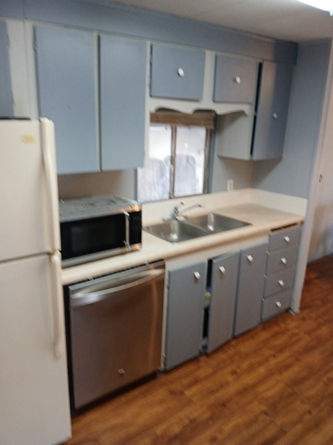 A kitchen with a white refrigerator and a stainless steel dishwasher.