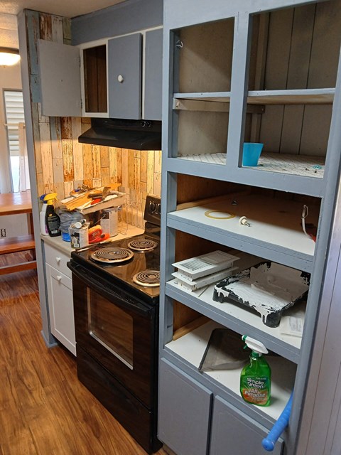 A kitchen with a black stove top oven and a wooden floor.
