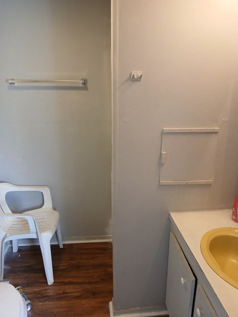 A white plastic chair is in a bathroom with a sink and toilet.