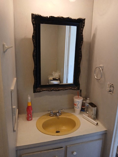 A bathroom sink with a yellow bowl and a mirror above it.