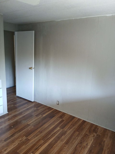 A room with a white door and wooden floors.