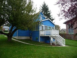 a blue house with a deck and a tree