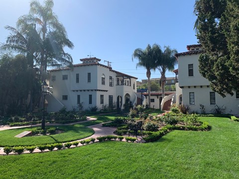 a mansion with a garden and palm trees in front of it
