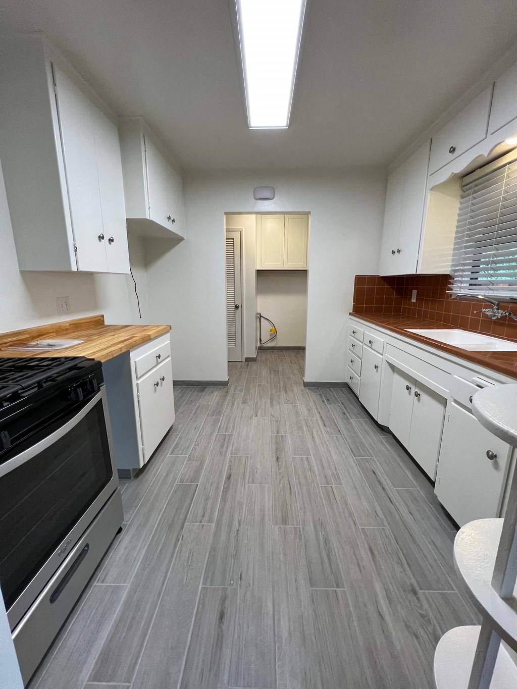 A kitchen with white cabinets and a wooden counter top.