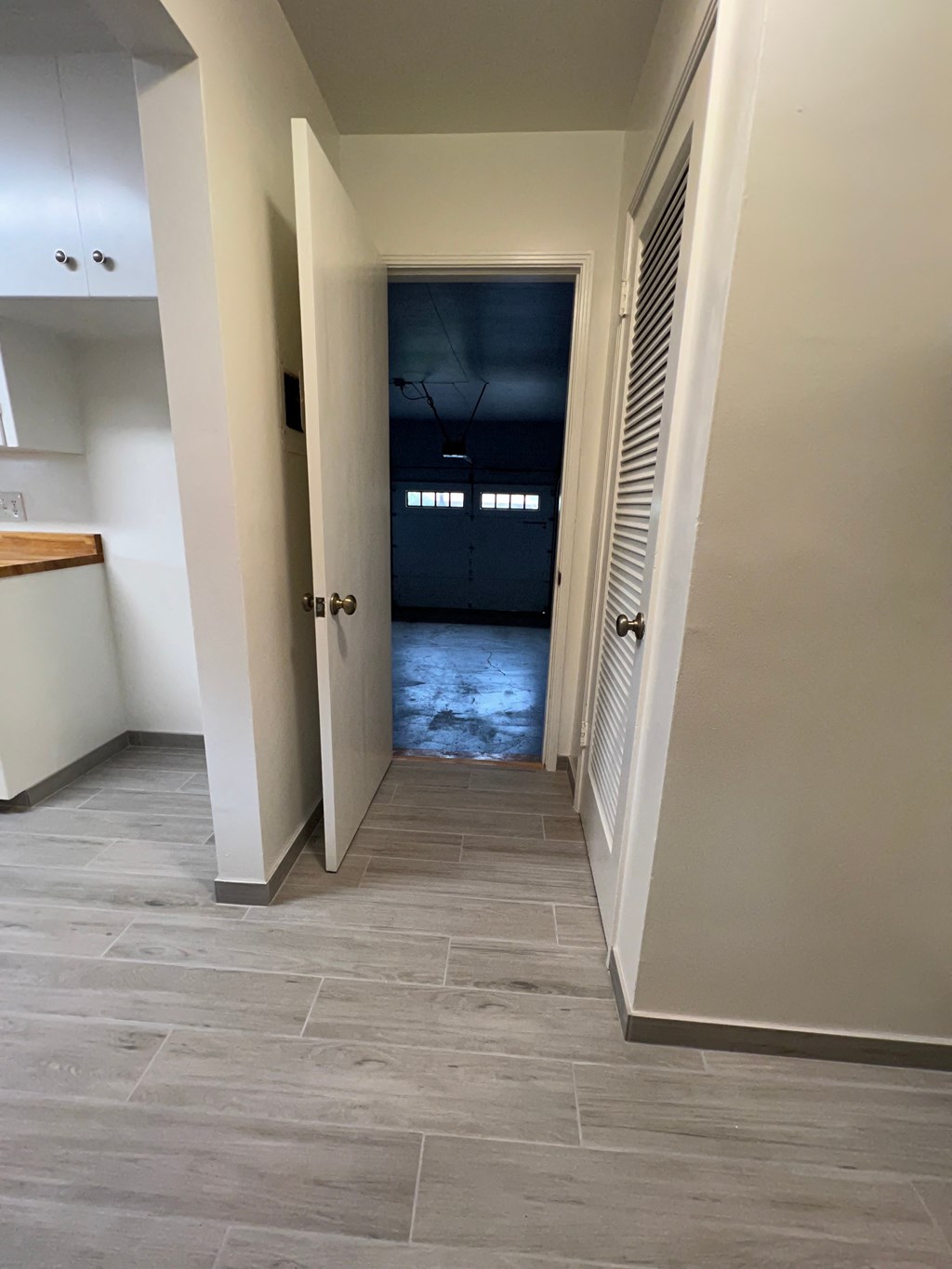 A hallway with a wooden floor and white walls.
