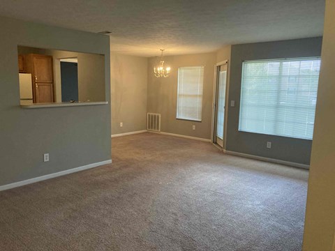 an empty living room with a chandelier and a window