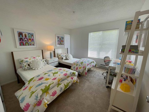 A bedroom with two beds and a bookshelf.