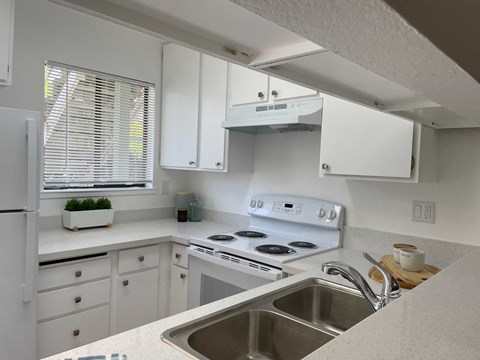 A kitchen with white cabinets and a stainless steel sink.