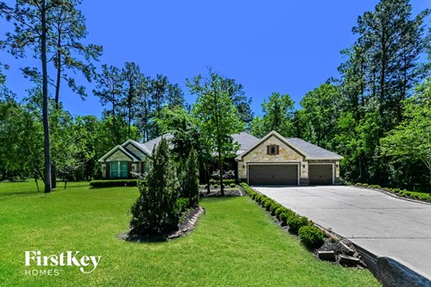 A house with a driveway and a garage is surrounded by trees.