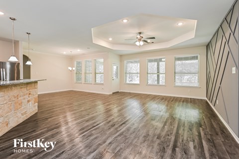 A spacious room with wooden floors and a ceiling fan.