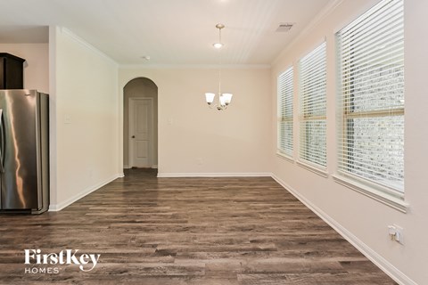 A spacious room with wooden flooring and a refrigerator on the left side.