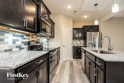 a kitchen with black cabinets and granite counter tops and a sink