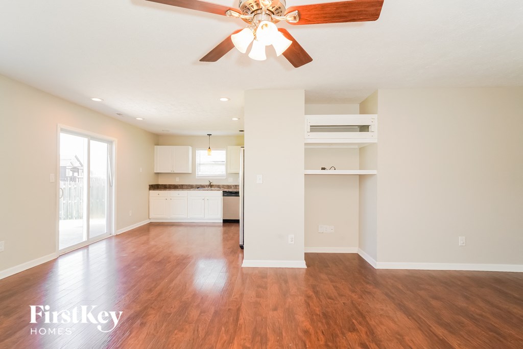 A spacious room with a ceiling fan and wooden flooring.