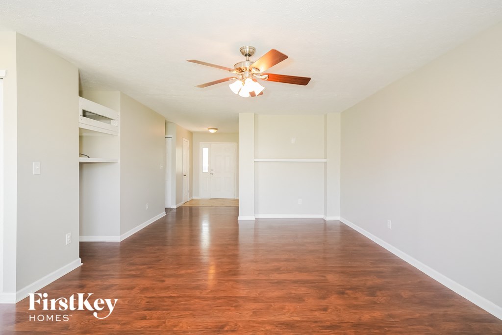 A spacious room with a ceiling fan and wooden flooring.