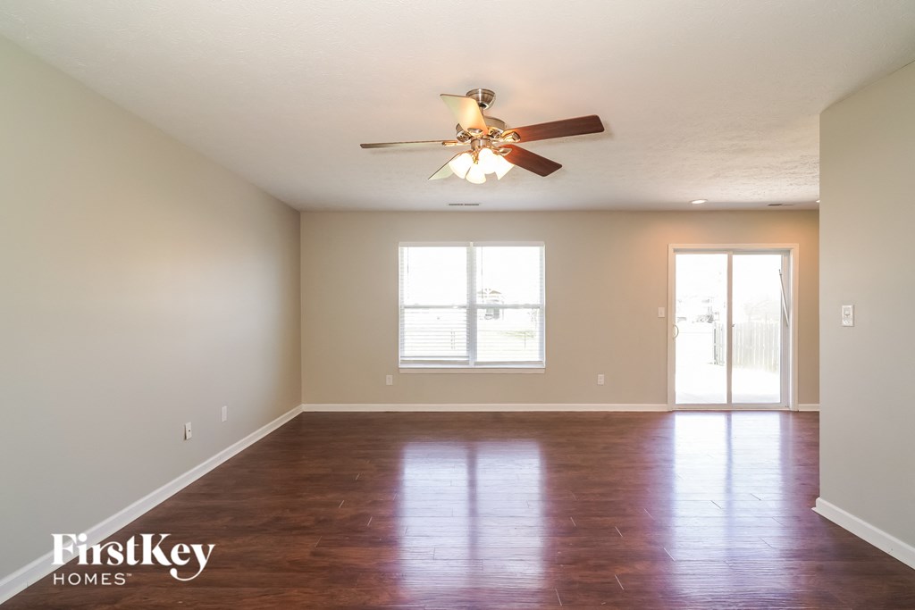 A room with a ceiling fan and wooden flooring.