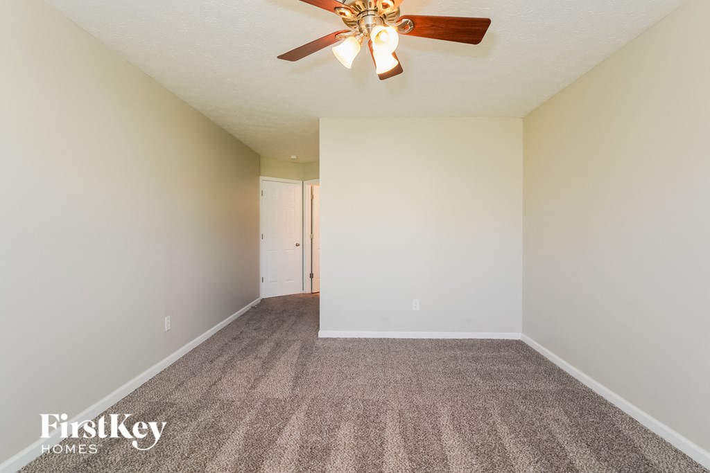 A room with a carpet floor and a ceiling fan.