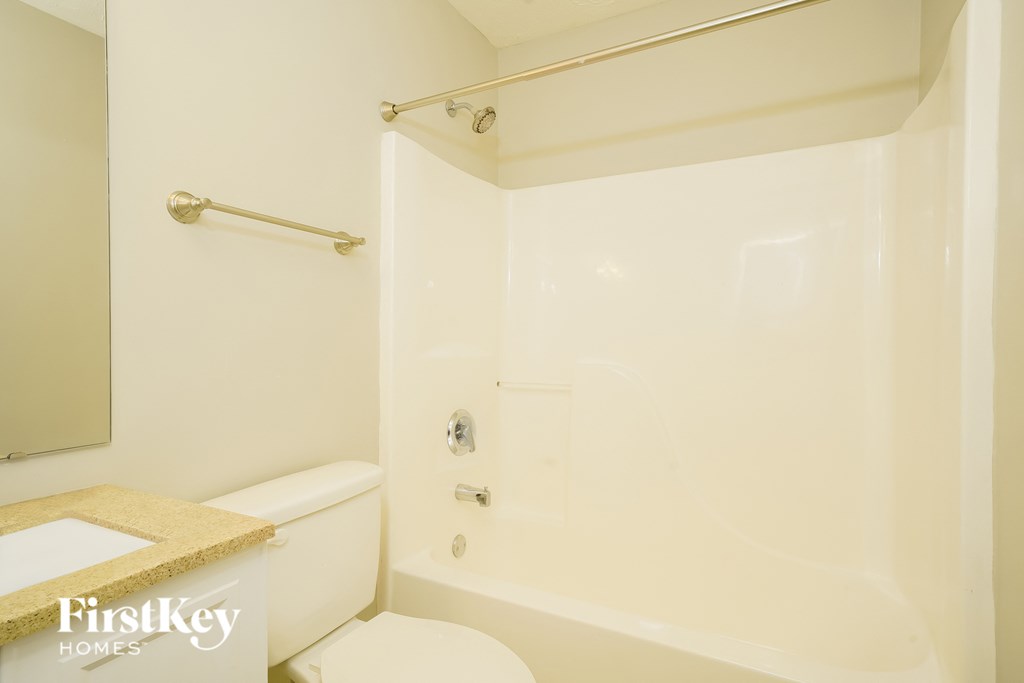 A white bathroom with a toilet, tub, and towel rack.