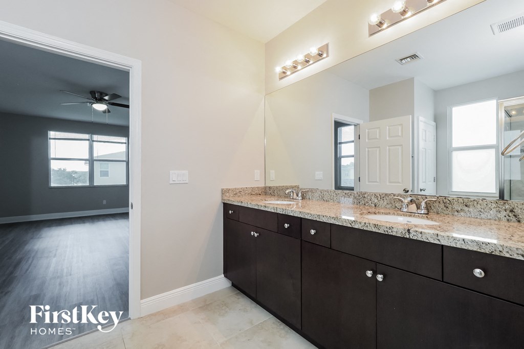 the master bathroom has a large mirror and granite counter tops