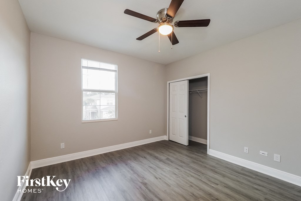 an empty living room with a ceiling fan and a closet