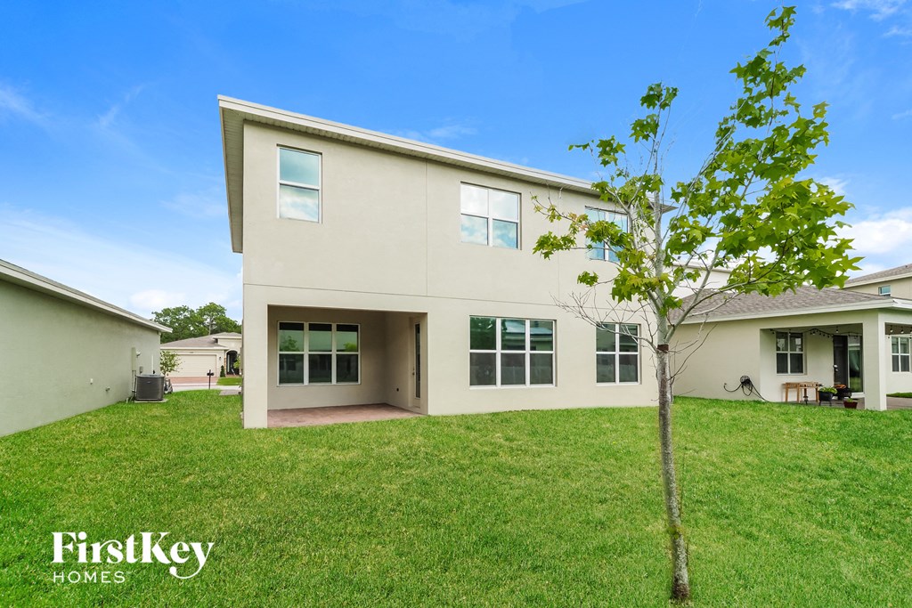 a beige house with a small tree in the yard