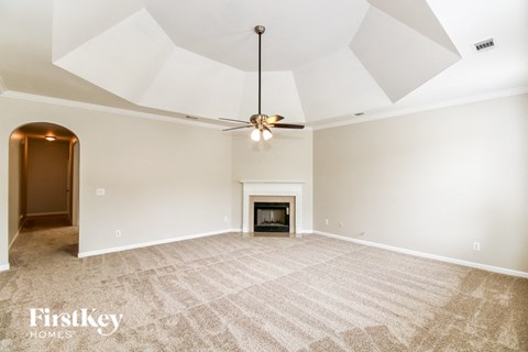 A spacious room with a fireplace and a ceiling fan.