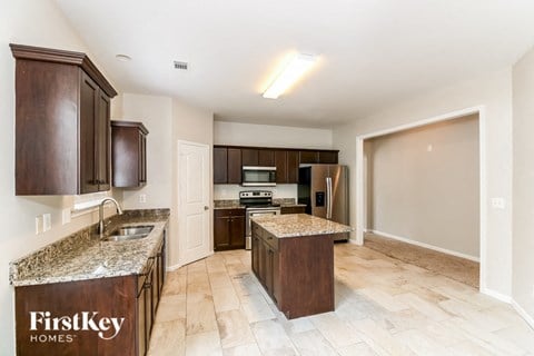 A kitchen with a granite counter top and wooden cabinets.