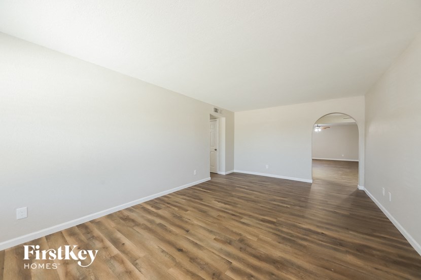 a spacious living room with white walls and wood flooring