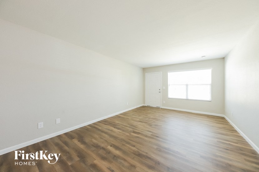the spacious living room with wood flooring and white walls