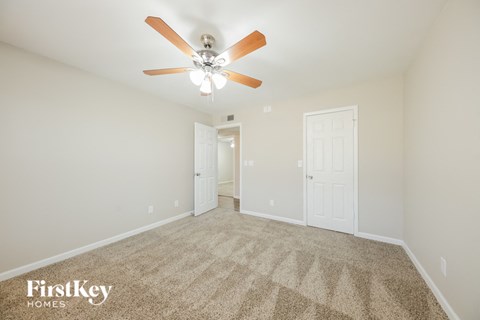 a spacious living room with carpet and a ceiling fan
