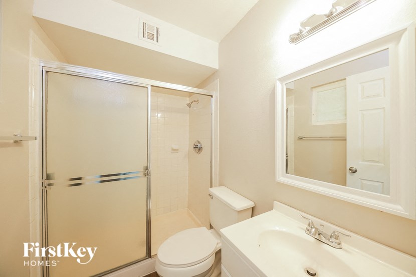 a white bathroom with a shower toilet and sink