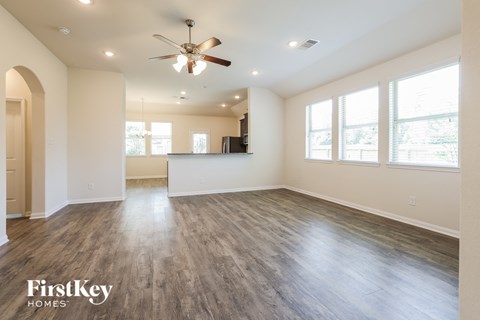 A spacious room with a ceiling fan and wooden flooring.