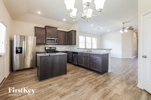 A kitchen with a refrigerator, microwave, and cabinets.