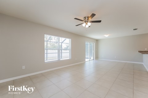 a clean and empty living room with a ceiling fan