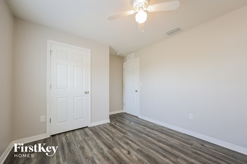 a bedroom with a white door and a ceiling fan