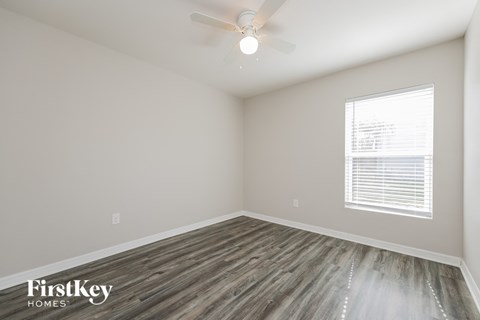 the spacious living room with wood flooring and a ceiling fan