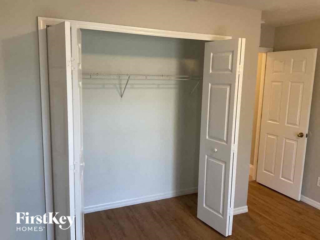 an empty bedroom with a closet and a door open to a closet with a white