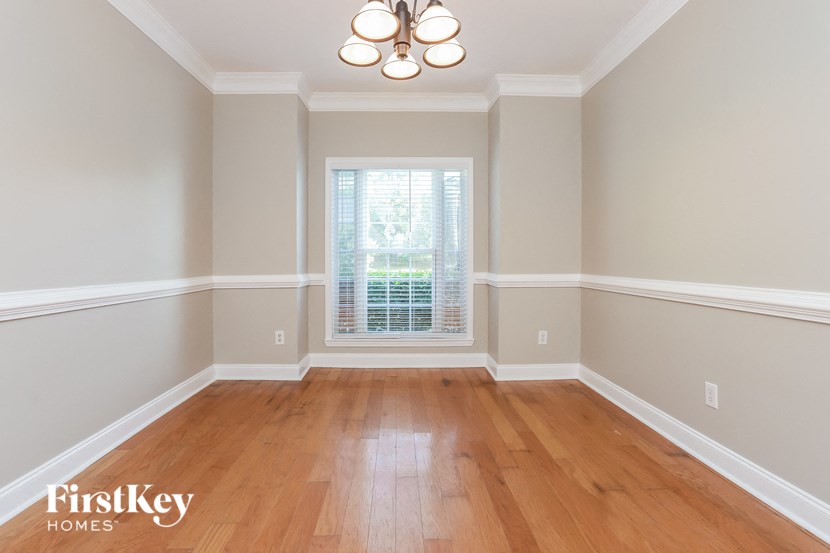 an empty dining room with wood floors and a window