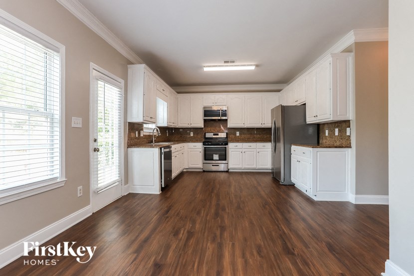 an empty kitchen with white cabinets and a wood floor
