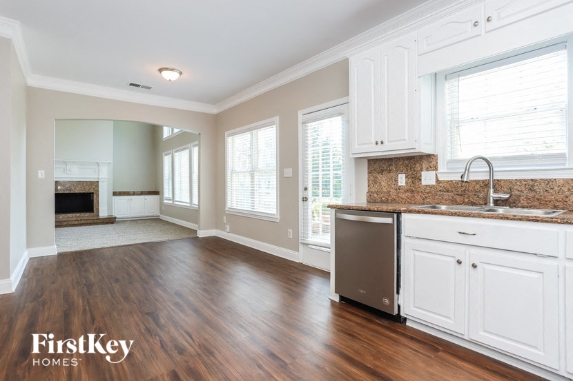a kitchen and living room with white cabinets and wood flooring