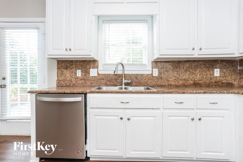 a white kitchen with granite counter tops and white cabinets