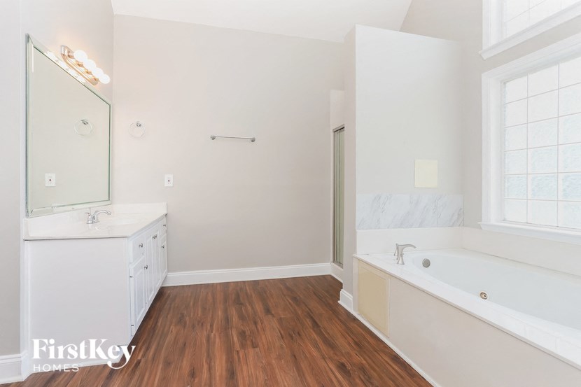 a white bathroom with a tub and a sink and a mirror