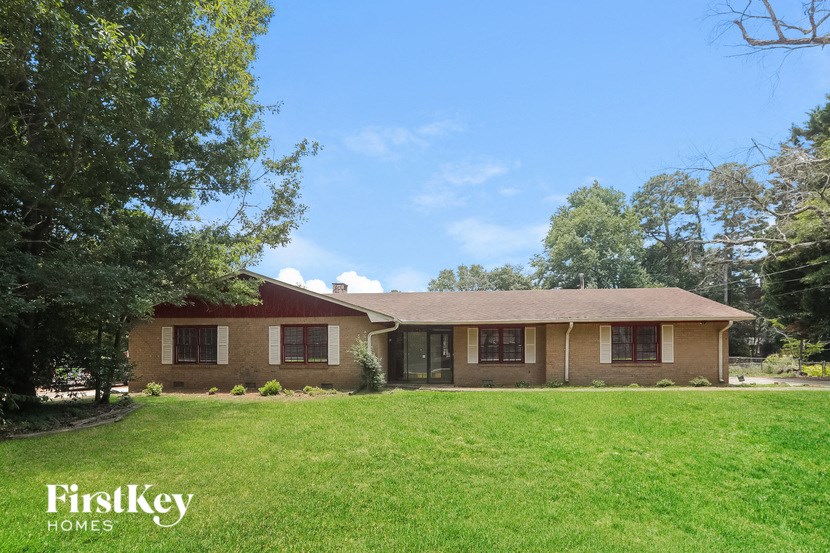 a brown house with a green lawn and trees