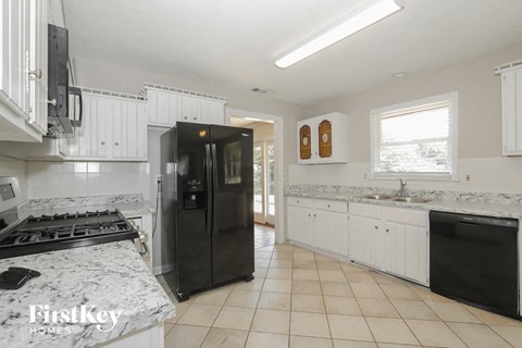a kitchen with white cabinets and a black refrigerator