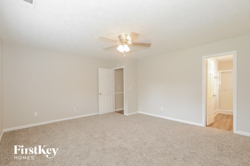 an empty living room with a ceiling fan and a door to a closet