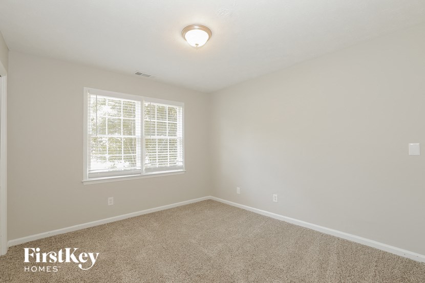 a bedroom with a large window and a carpeted floor