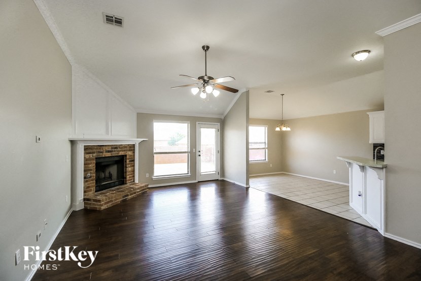 A spacious room with a fireplace and wooden floors.