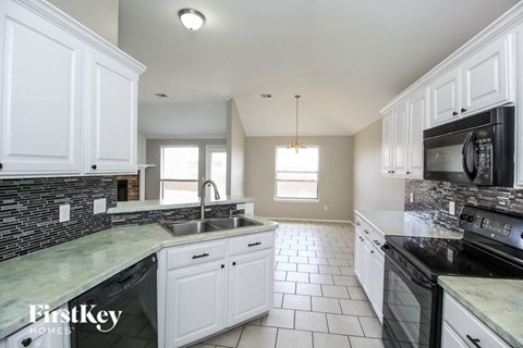 A kitchen with white cabinets and a black stove top oven.