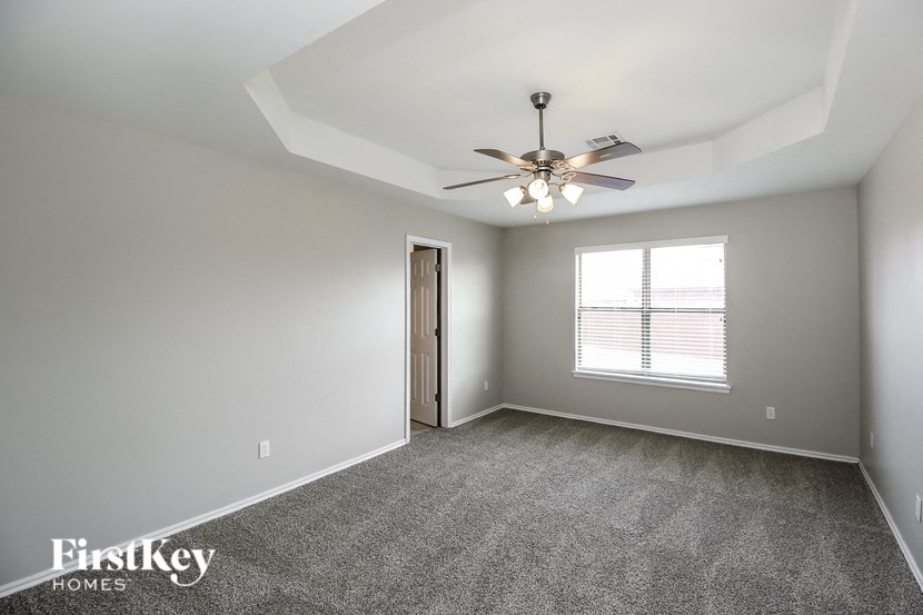 A spacious room with a ceiling fan and carpeted floor.