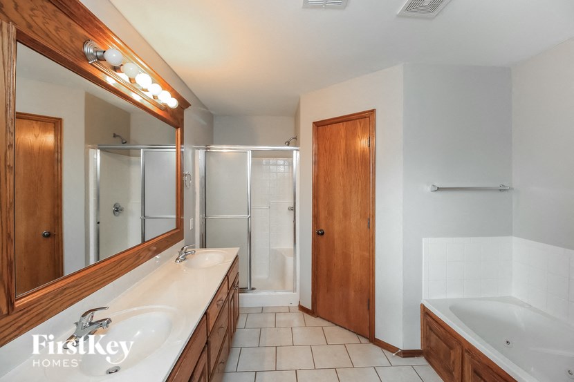 A bathroom with a white sink and a wooden vanity.